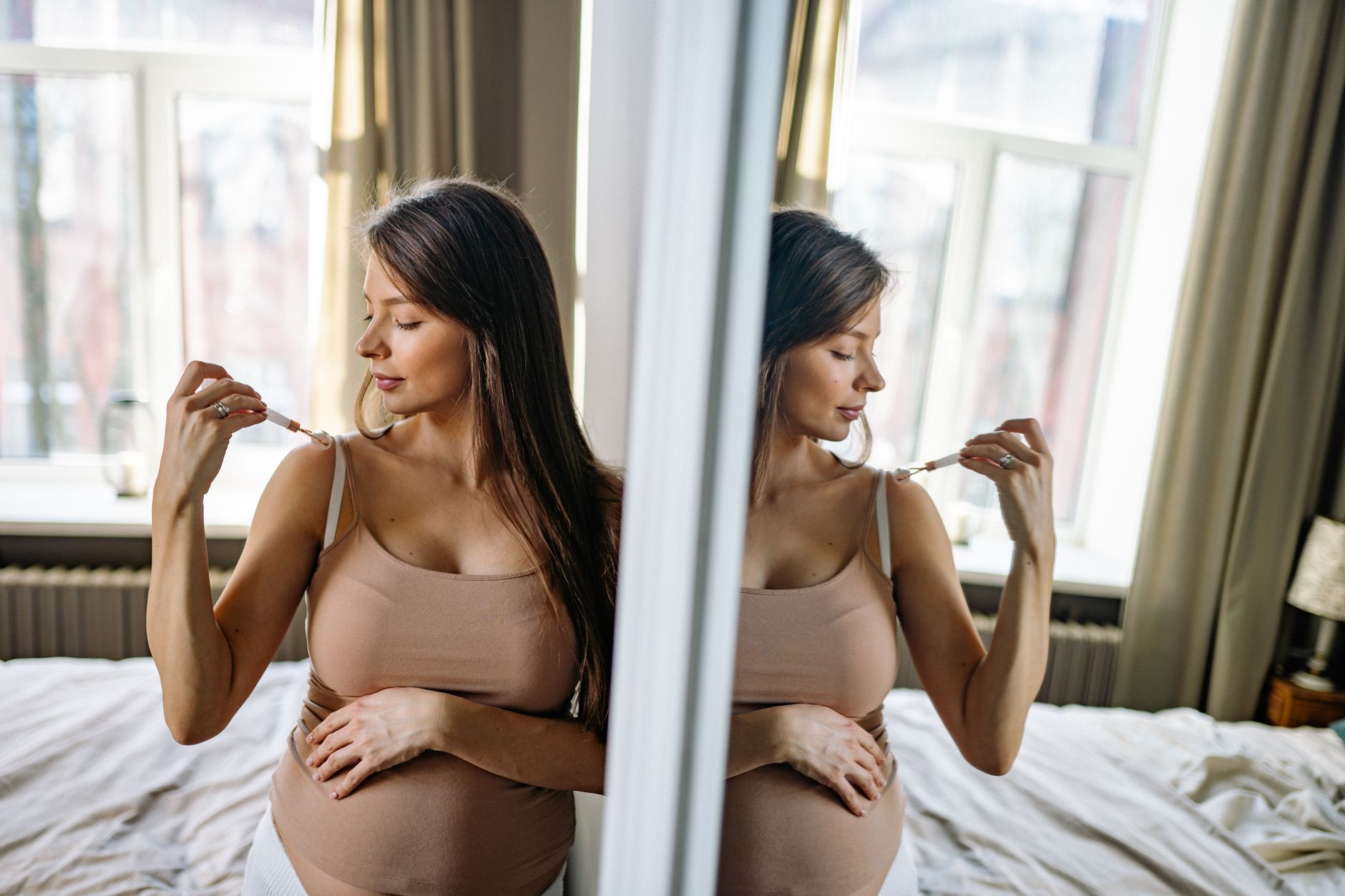 Mulher grávida a fotografar a barriga em frente ao espelho, com a mesma luz do mês anterior.