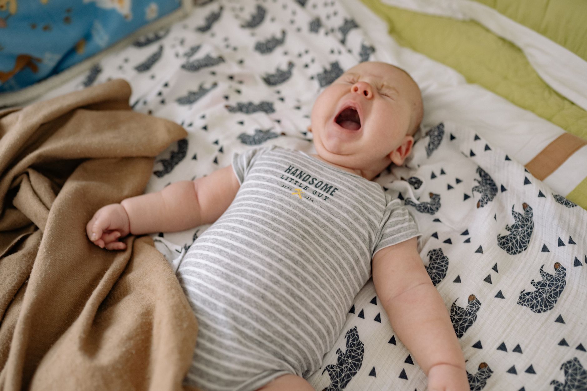 Un bébé fatigué se frotte les yeux dans son lit l'après-midi.