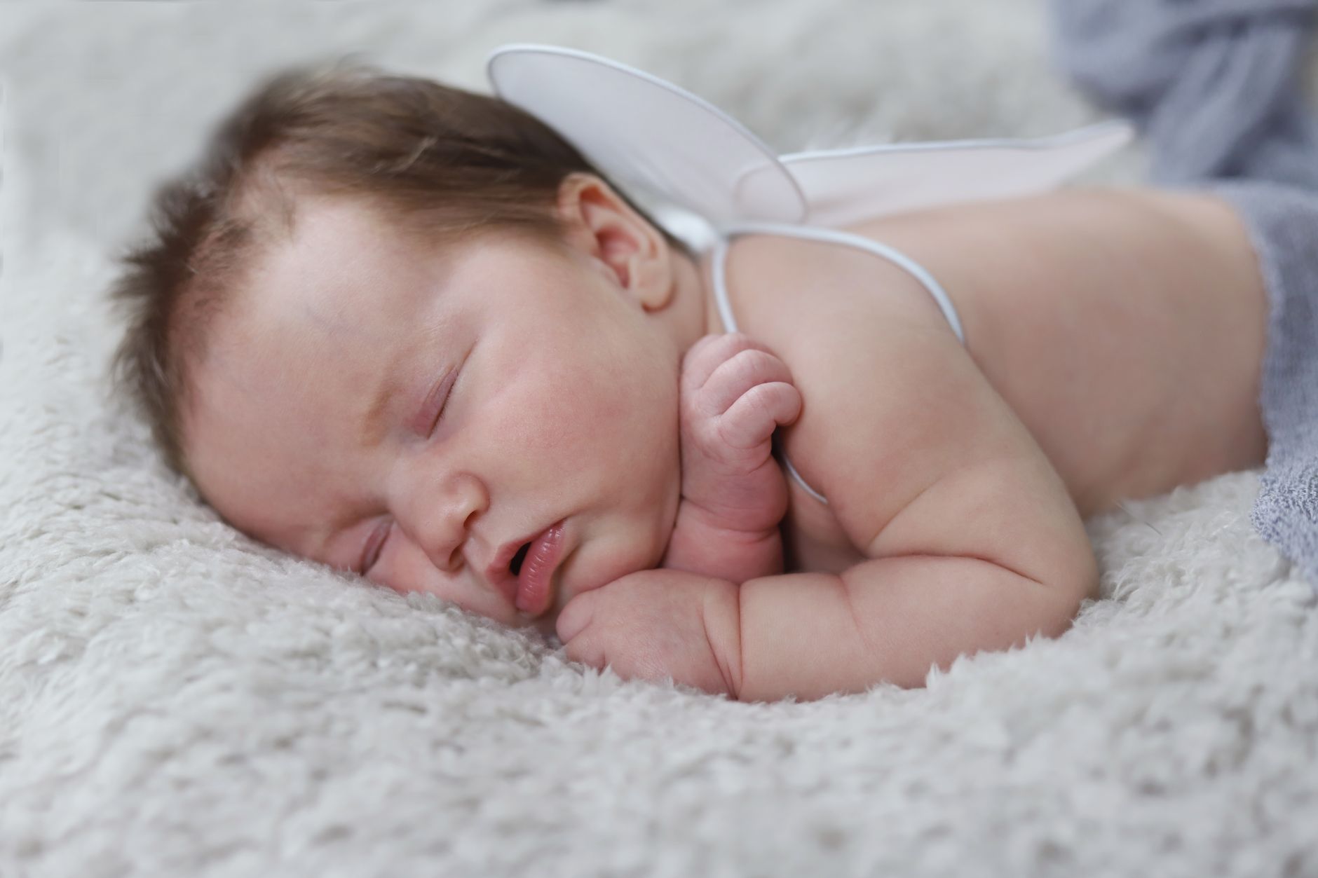 Ein zwei Monate altes Baby schläft auf dem Rücken in seinem Bettchen.