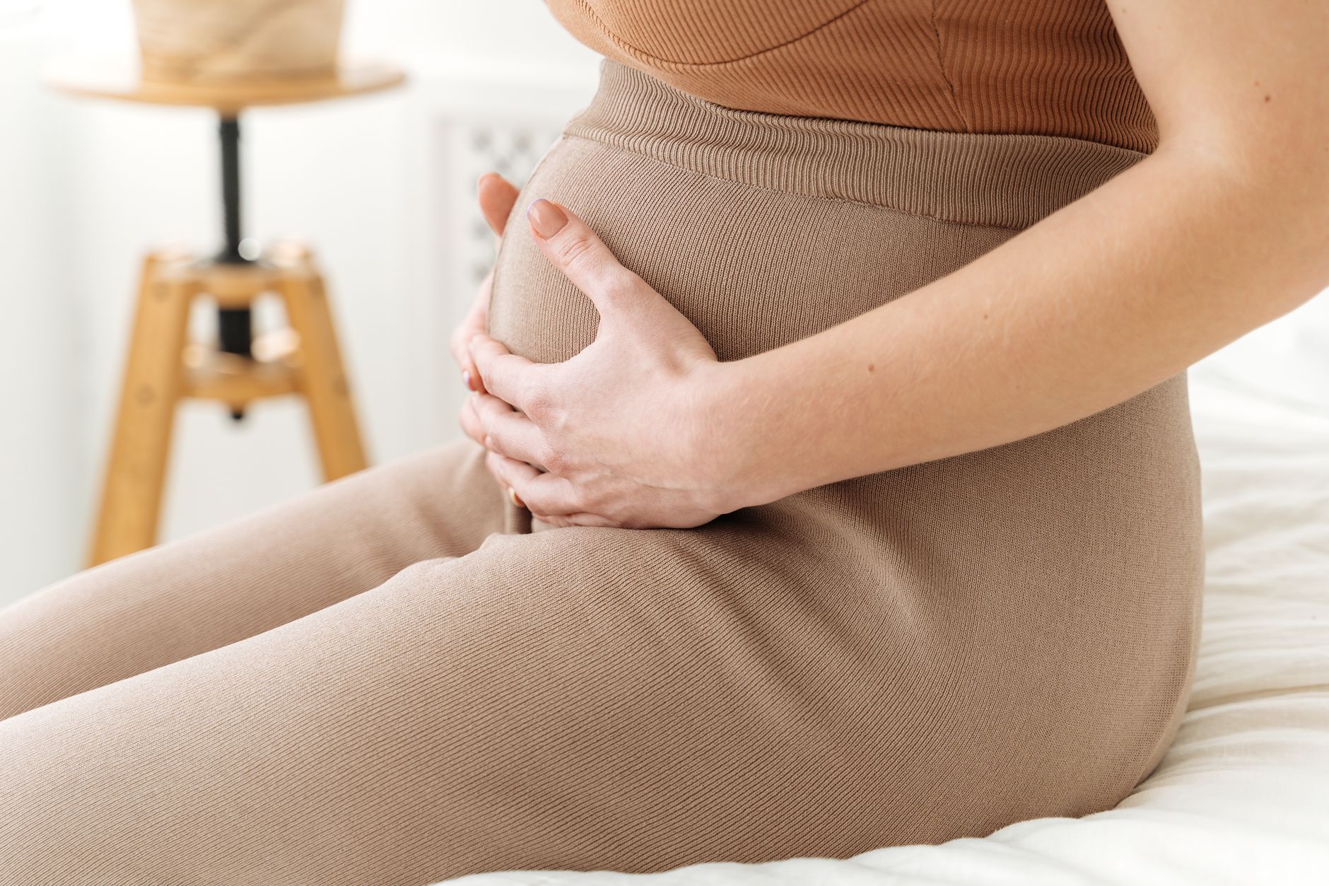 Zwei Hände formen ein Herz auf einem schwangeren Bauch